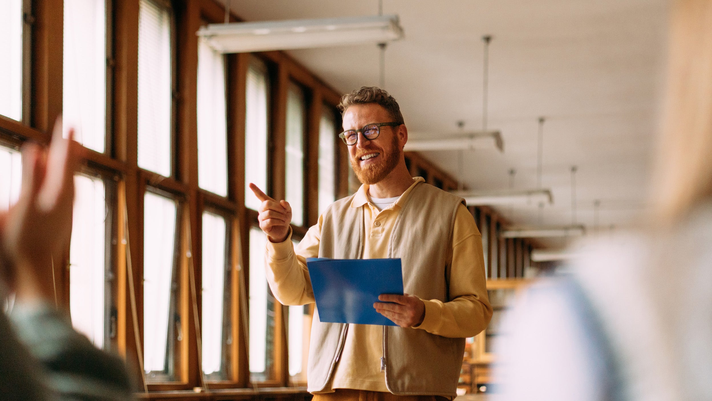 Man presenting to a group in a bright workspace.