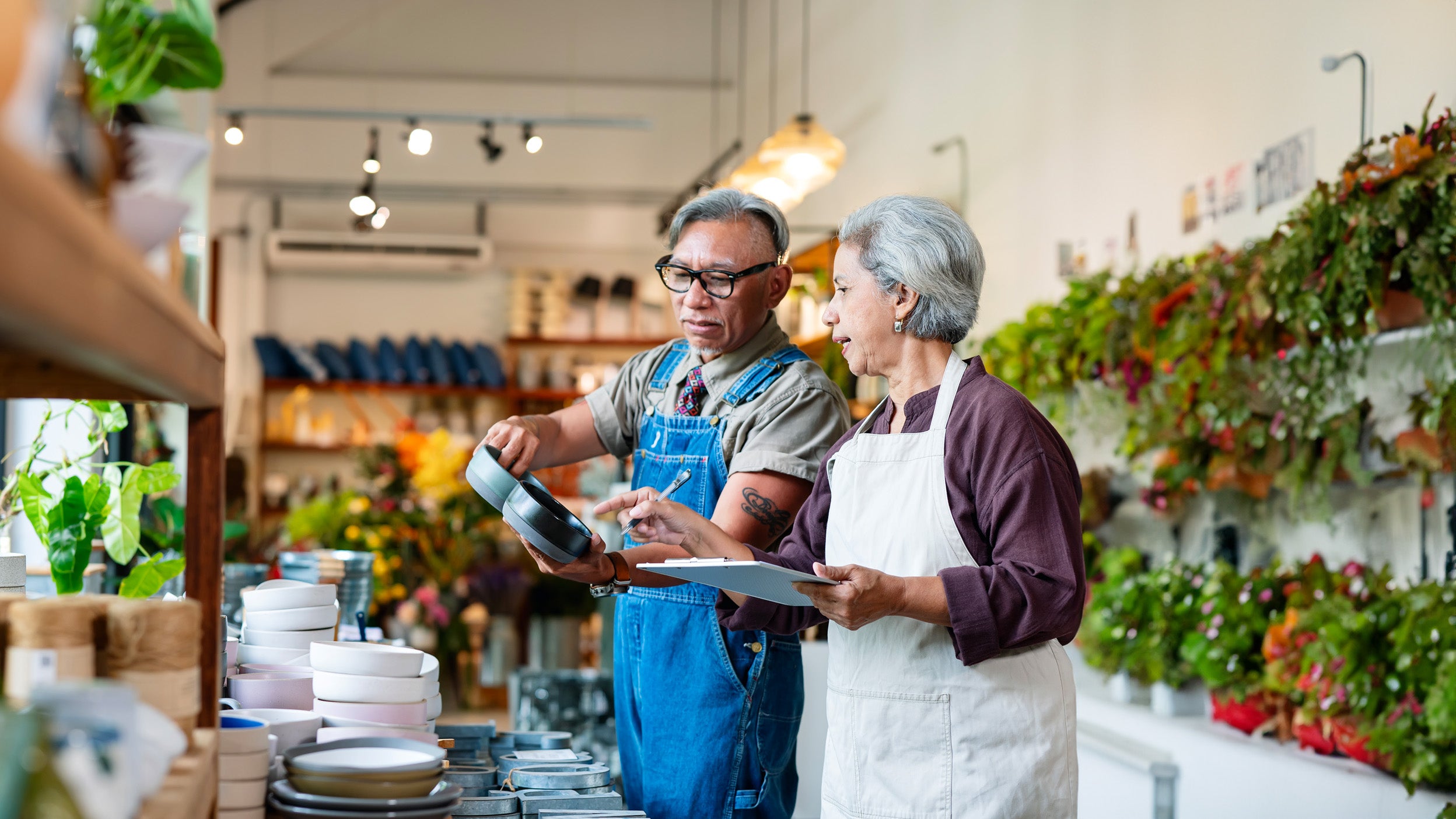Two people examining pots in a plant shop.