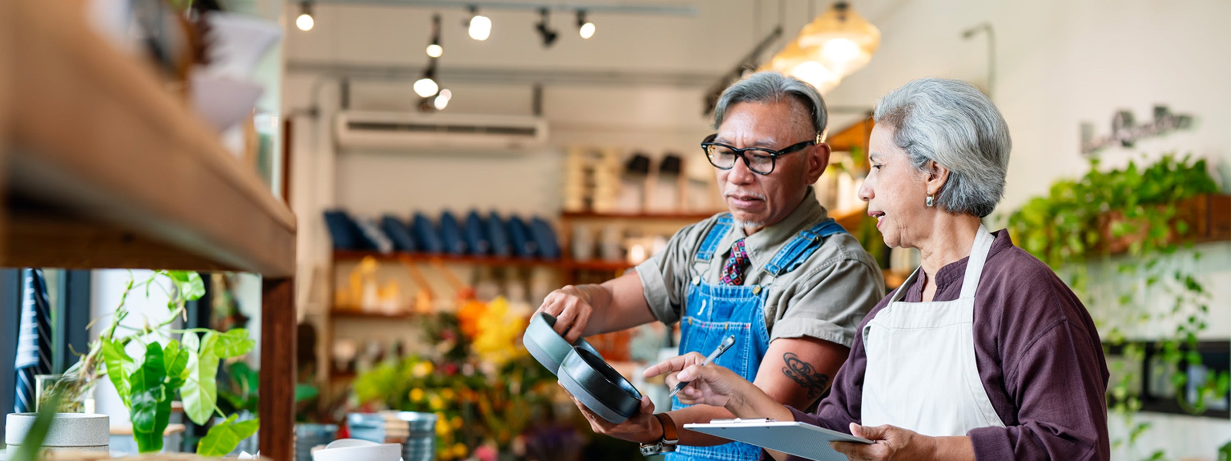 Two people examining pots in a plant shop.