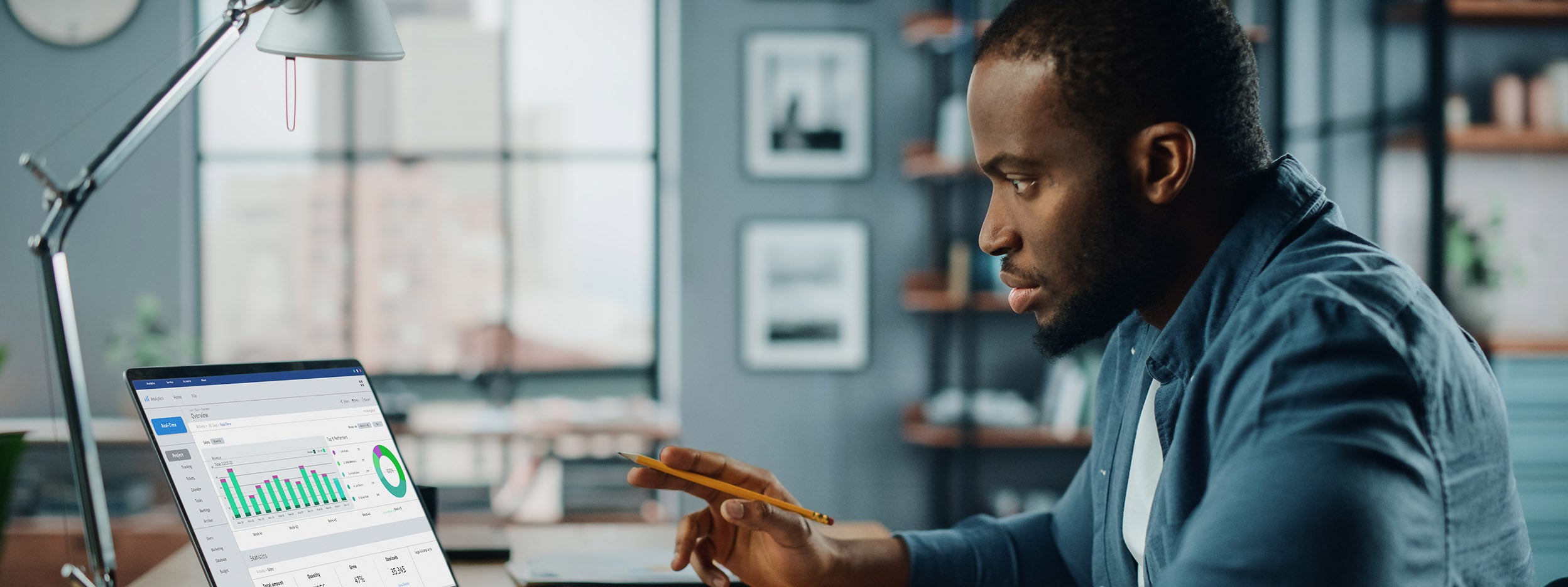 man reading statistical data from laptop and a paper