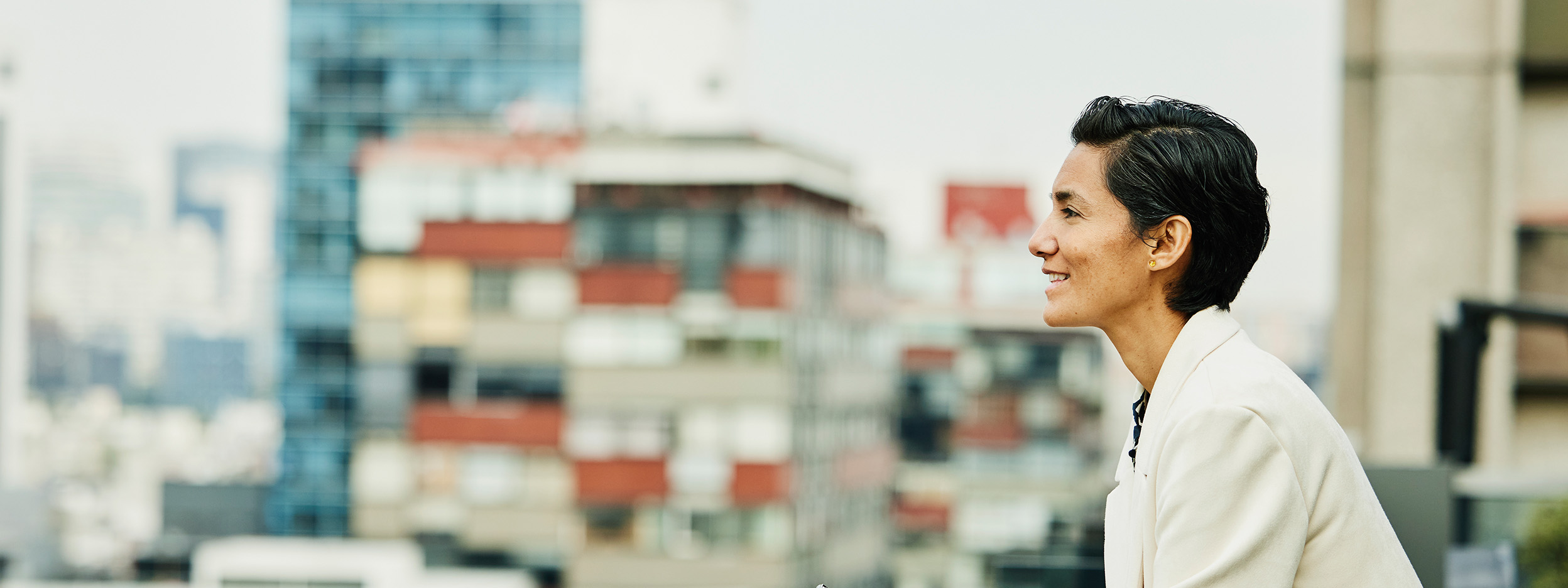 Medium wide shot businesswoman looking at cityscape from rooftop deck of office building