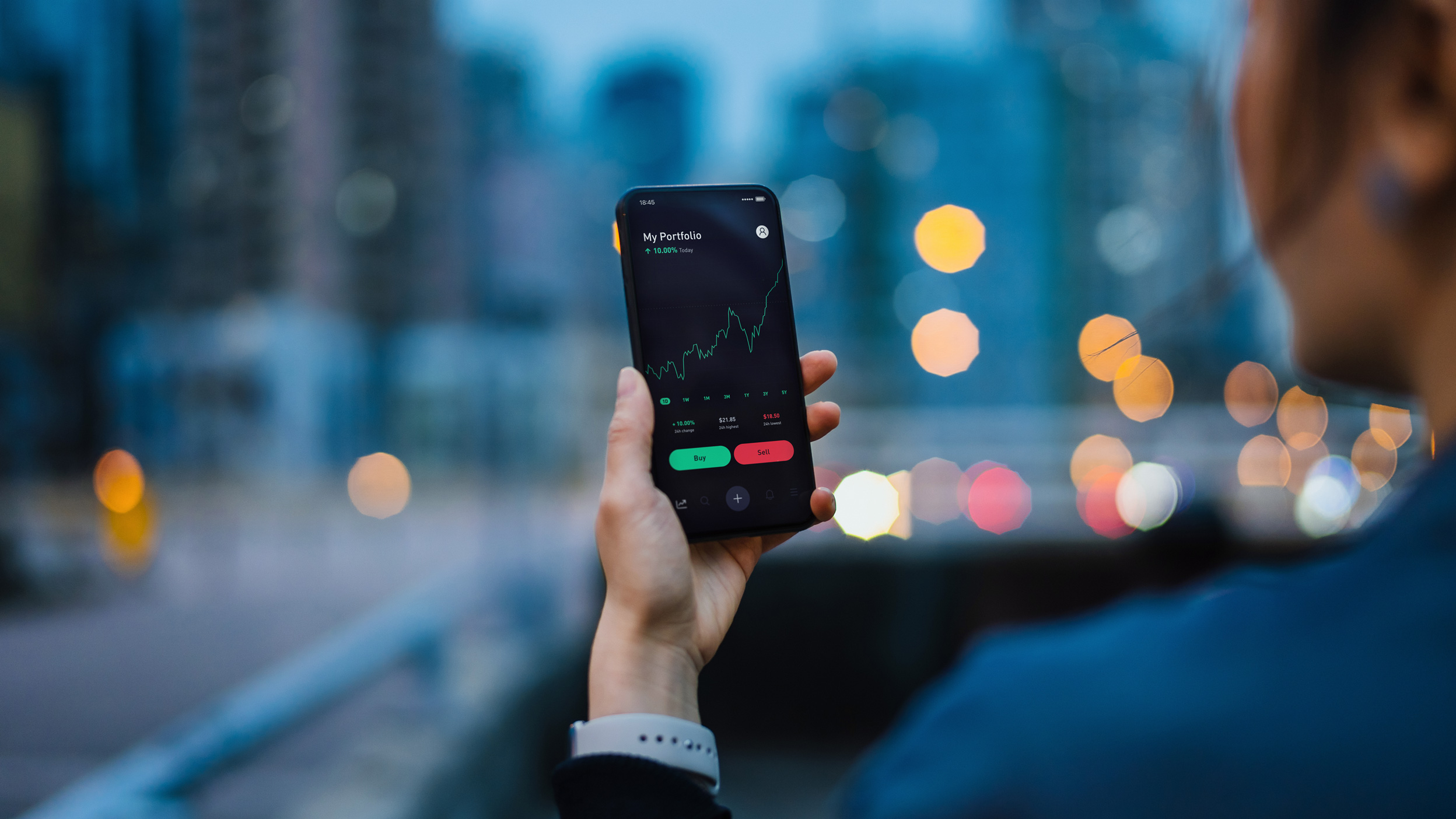 Hand holding phone with stock chart.