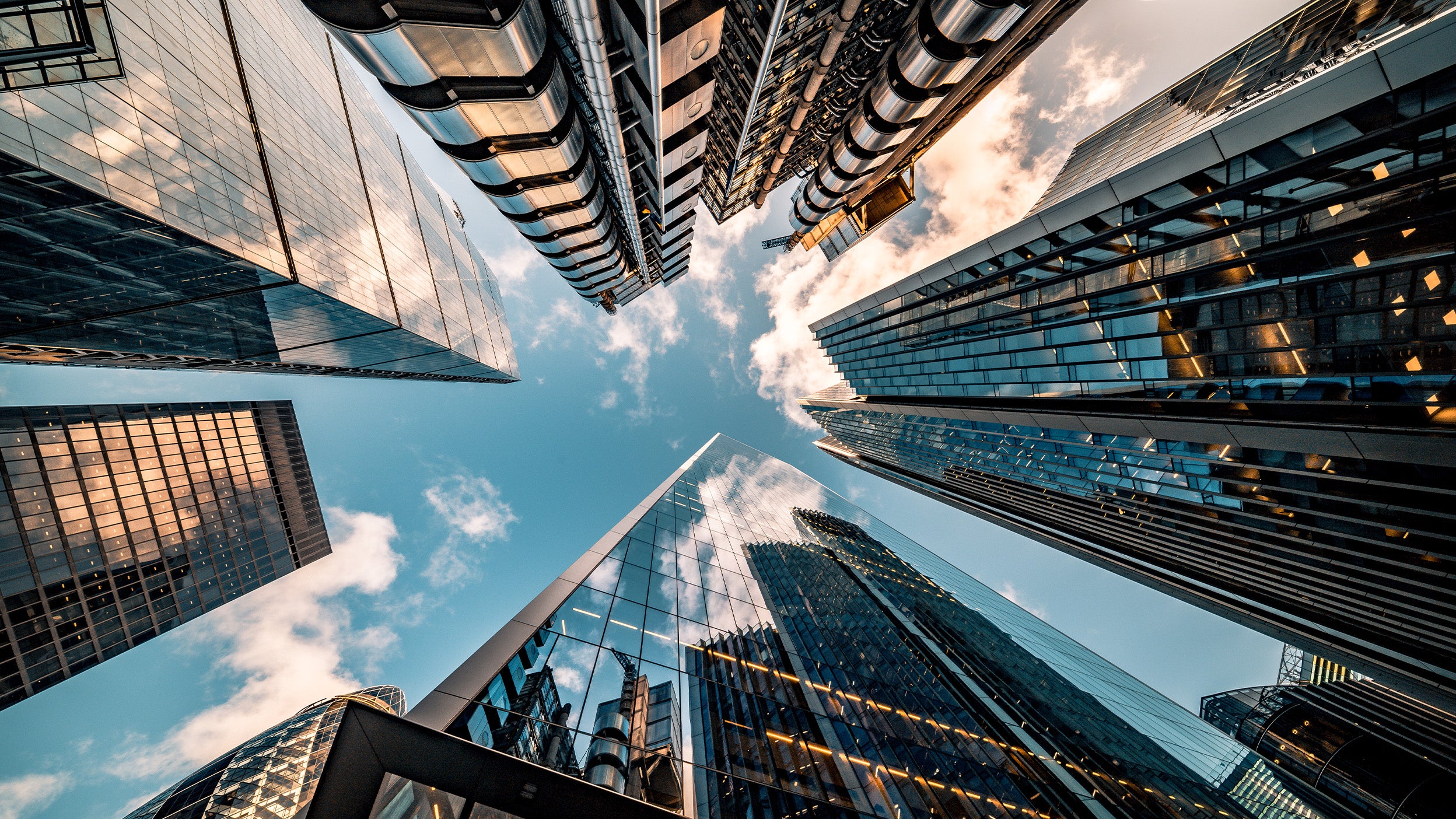 Looking up at modern glass skyscrapers against a blue sky