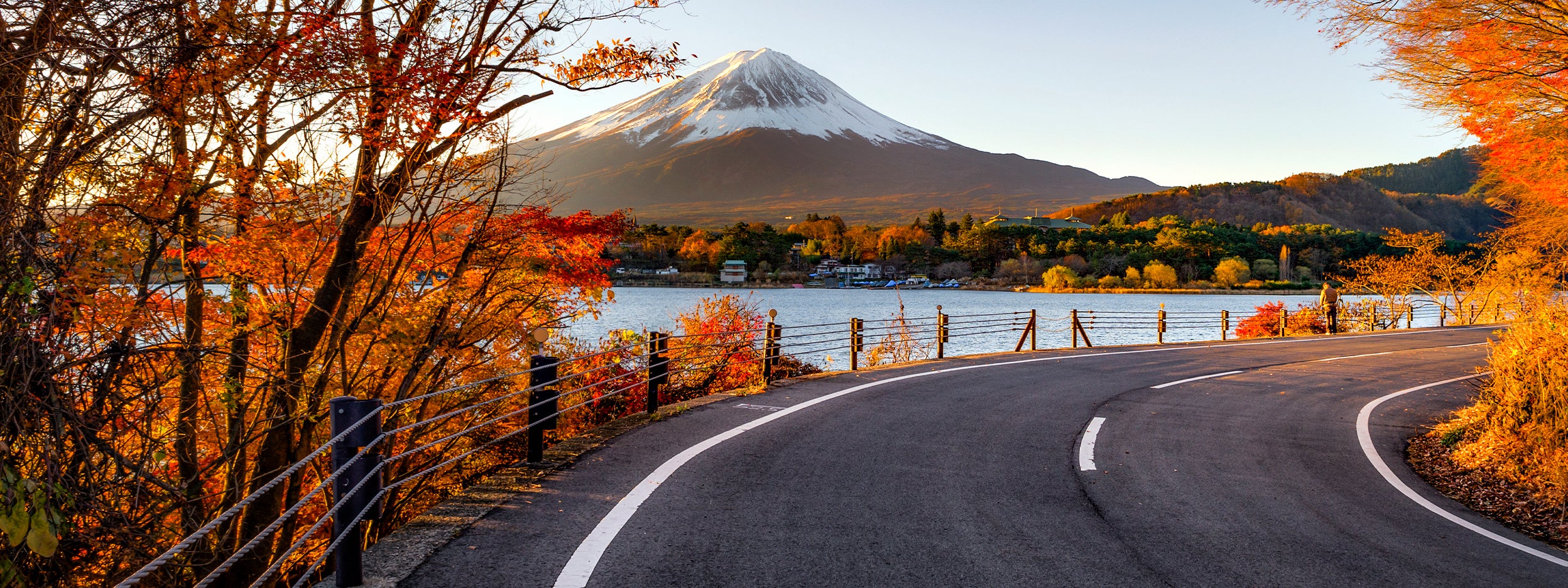 A road with lake on side with mountains
